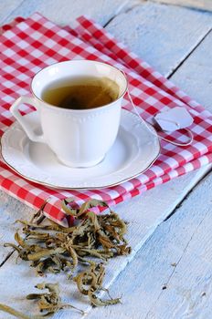 Cup of chamomile and herbs on wooden table in the kitchen.