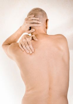 Man massaging his top back, the trapezius muscle, because of a thoracic vertebrae pain due to a displacement of a dorsal vertebra rubbing on a nerve