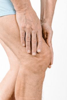 Athlete man massaging a painful  quadriceps and the knee after a sport accident. It could be a quadriceps tendinopathy, a muscle elongation, a medial meniscus tears or bursitis