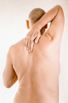 Man massaging his top back, between the shoulders, because of a thoracic vertebrae pain due to a displacement of a dorsal vertebra rubbing on a nerve