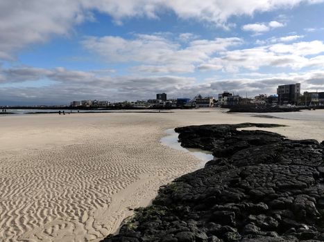 Vanishing point for black volcanic rock and sand prints in Hyeopjae beach with cobalt blue sea in Jeju Island, South Korea