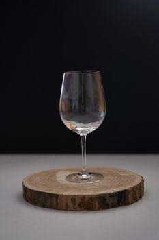 Glass of wine on black background, low key, wooden stump