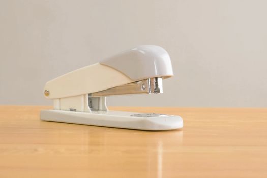 A white stapler is on the table. Stationery.