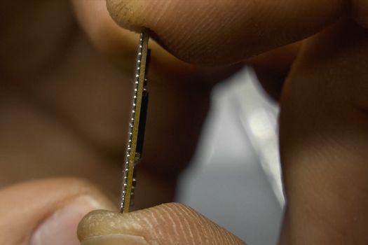 The recovered computer microprocessor chip is in the hands of a man.