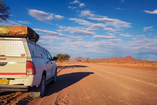 Karas, Namibia - March 30, 2019: Typical 4x4 rental car in Namibia equipped with camping gear and a roof tent parks on a dirt road in the Karas Region in Namibia.