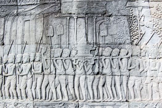 Ancient Khmer bas relief carving of a religious parade with worshippers carrying an ark. Wall of Bayon Temple, Angkor Thom, Siem Reap, Cambodia.