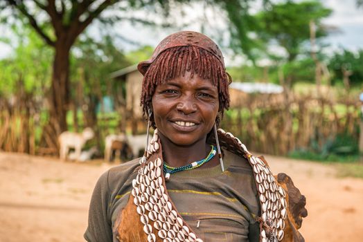 TURMI, OMO VALLEY, ETHIOPIA - MAY 5, 2015: Portrait of a woman from the Hamar tribe in south Ethiopia. Married hamar women apply red clay to their hair and fashion it into long tufts.