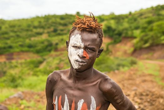 OMO VALLEY, ETHIOPIA - MAY 7, 2015 : Young boy from the African tribe Mursi with traditionally painted face in Mago National Park, Ethiopia.