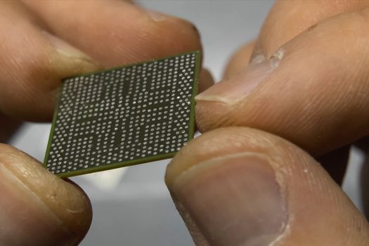 The recovered computer microprocessor chip is in the hands of a man.