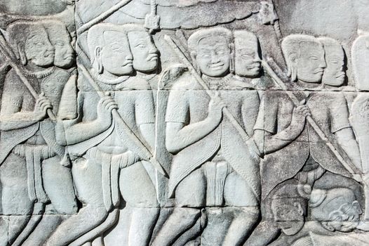 Ancient Khmer bas relief carving showing the Khmer army going into battle. Some of their colleagues are lying drunk on the floor. Outer wall of Bayon Temple, Angkor Thom, Siem Reap, Cambodia.