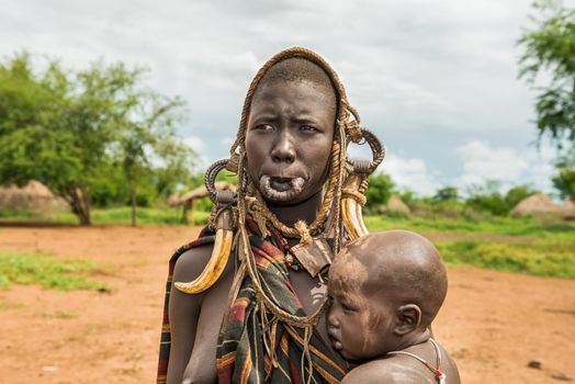 OMO VALLEY, ETHIOPIA - MAY 7, 2015 : Woman from the african tribe Mursi with her baby