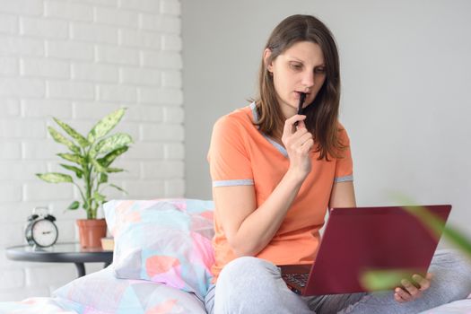 Girl watching a video tutorial and thoughtfully nibbles a marker