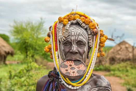 OMO VALLEY, ETHIOPIA - MAY 7, 2015 : Woman from the african tribe Mursi with big lip plate in her village.