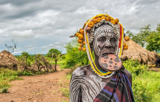 OMO VALLEY, ETHIOPIA - MAY 7, 2015 : Woman from the african tribe Mursi with a big lip plate in her village.