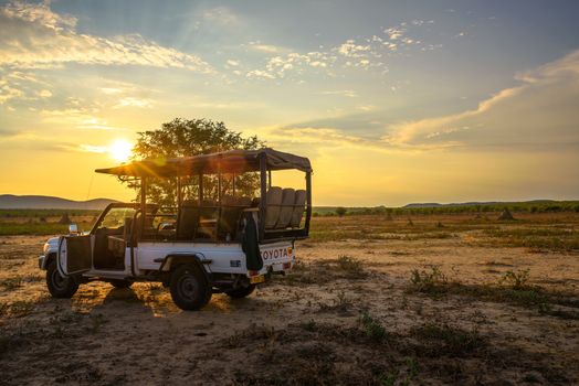 Hobatere, Namibia - April 1, 2019 : African 4x4 safari vehicle having a break in the Hobatere game reserve with dramatic sunset in the background.