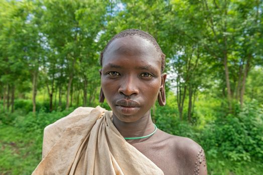 SOUTHWESTERN ETHIOPIA - MAY 3, 2015 : Portrait of a young boy from the african tribe Suri with traditionally enlarged Ears