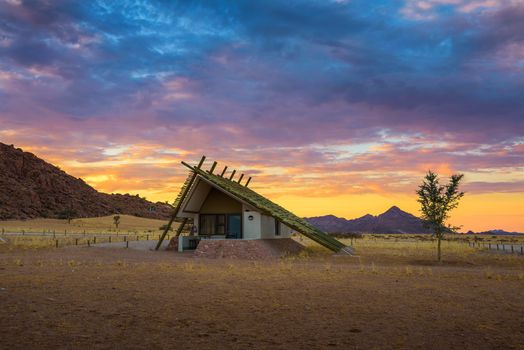 Sossusvlei, Namibia - March 29, 2019 : Sunrise above a small hut in a desert lodge near the Namib-Naukluft National Park close to Sossusvlei.