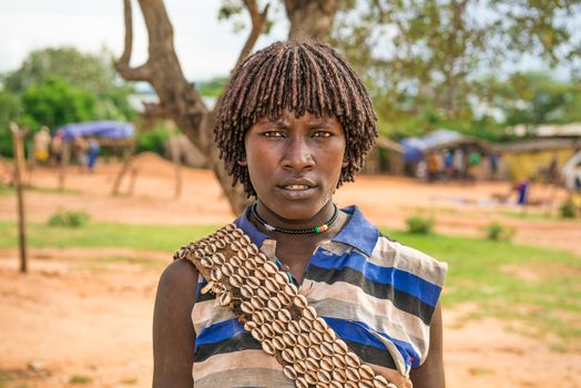 TURMI, OMO VALLEY, ETHIOPIA - MAY 5, 2015: Portrait of a woman from the Hamar tribe in south Ethiopia. Married hamar women apply red clay to their hair and fashion it into long tufts.