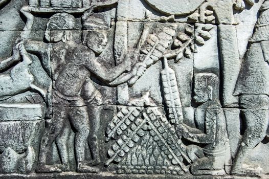 Ancient Khmer bas relief sculpture showing satay kebabs being grilled on a fire. Frieze on a wall of Bayon Temple, Angkor Thom, Siem Reap, Cambodia.
