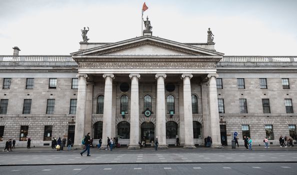 Dublin, Ireland - February 12, 2019: Architecture detail of the Central Post Office in the historic city center where people walk on a winter day