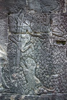 Ancient Khmer bas relief carving of two men hiding up trees after being pursued by a tiger. Wall of Bayon Temple, Angkor Thom, Siem Reap, Cambodia.