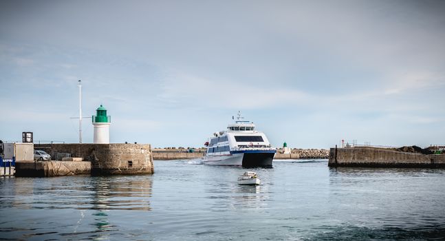 Ile d Yeu, France - September 16, 2018: ferry that enters the harbor of the island of Yeu where travelers are sitting to admire the show on a summer day