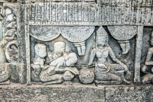 Ancient bas relief carving showing a woman receiving Khmer Massage. Wall of Bayon Temple, Angkor Thom, Siem Reap, Cambodia.