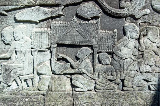 Ancient khmer bas relief carving showing a woman selling a large fish beside the Tonle Sap lake. Bayon Temple, Angkor Thom, Siem Reap, Cambodia.
