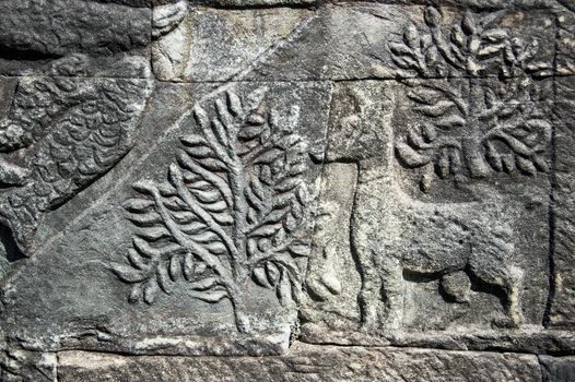 Ancient Khmer carving of a deer in the woods. Wall of Bayon Temple, Angkor Thom, Siem Reap, Cambodia.