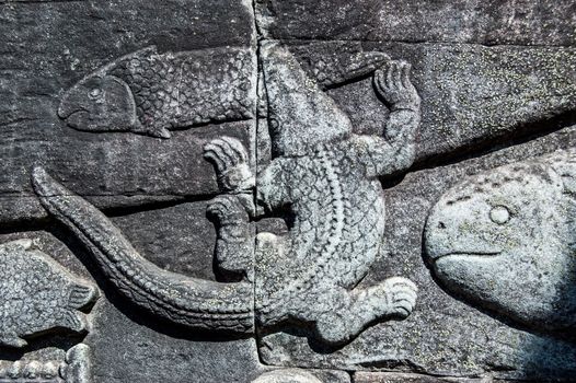 Ancient Khmer bas relief carving showing a crocodile catching a fish in the Tonle Sap lake. Bayon Temple, Angkor Thom, Siem Reap, Cambodia.