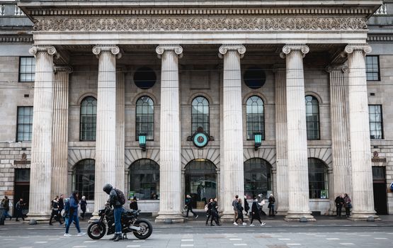 Dublin, Ireland - February 12, 2019: Architecture detail of the Central Post Office in the historic city center where people walk on a winter day