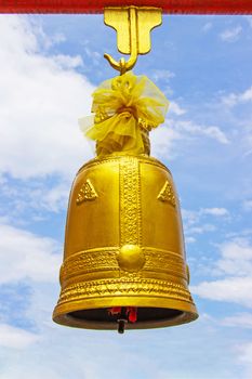 Golden bell hang with red iron beams large size with bright sky and cloud as the background.