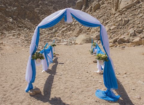 Setup of wedding day marriage aisle with drapes and arch in a remote arid desert environment