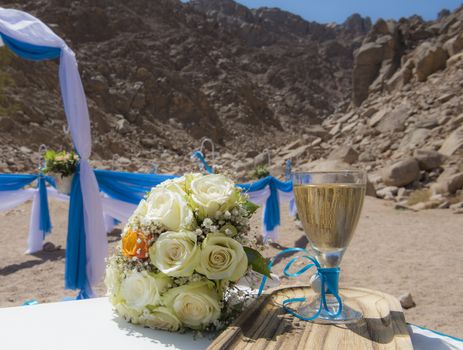 Setup of wedding day marriage ceremony with flower bouquet and champagne in remote arid desert environment