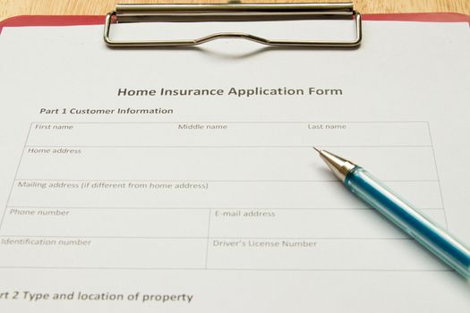 Home insurance application form with red file on wooden table