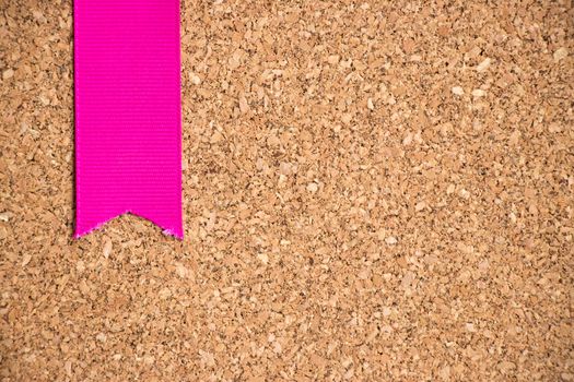 Pink ribbon on cork board texture background