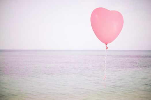Grunge pink balloon over sea sky background with retro filter effect
