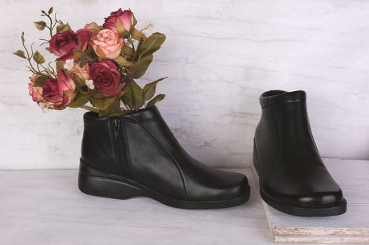 Rose bouquet and black leather shoes on grunge white background