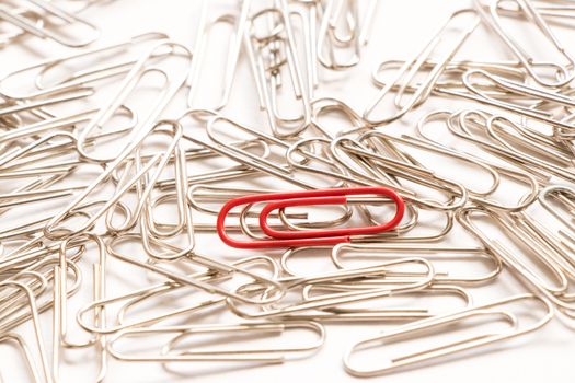 Red paper clip show different from the others on white background