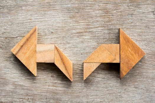 Tangram puzzle as two way arrow shape on wooden background