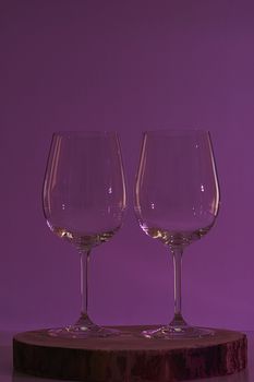 Two glasses of wine on violet background, warm tone, wooden stump