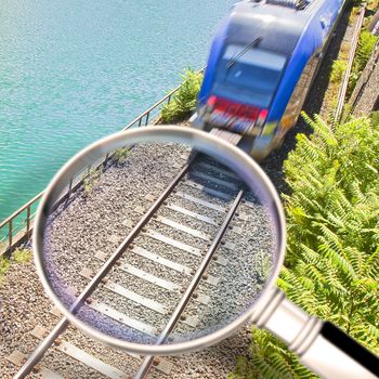 Railway seen from above with incoming train - concept image seen through a magnifying glass.