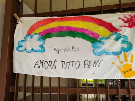 Turin, Piedmont, Italy. June 2020. Coronavirus pandemic. On the facades of the houses hang the sheets with the drawing of the rainbow and message everything will be fine. In Italian "Andrà tutto bene"