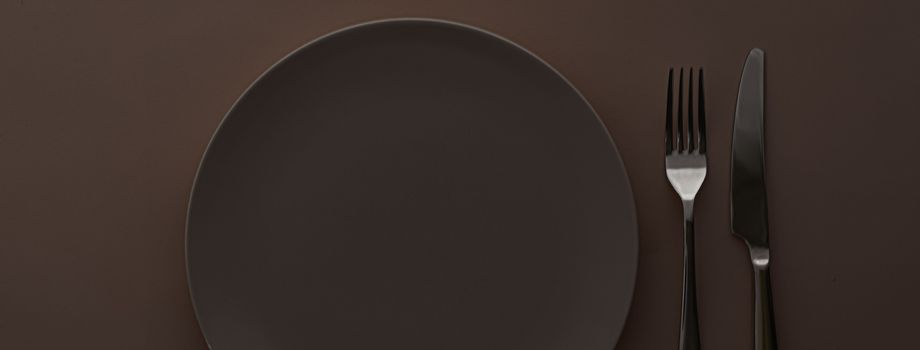 Empty plate and cutlery as mockup set on dark brown background, top tableware for chef table decor and menu branding design