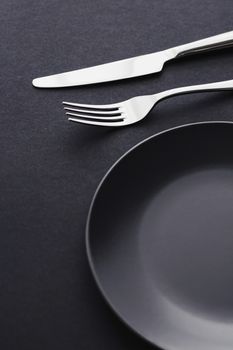 Empty plates and silverware on black background, premium tableware for holiday dinner, minimalistic design and diet concept