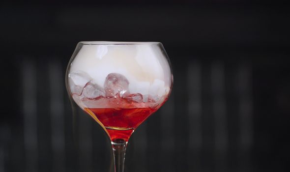 Close up glass of red cocktail with dry ice. Bar drinks and cocktails
