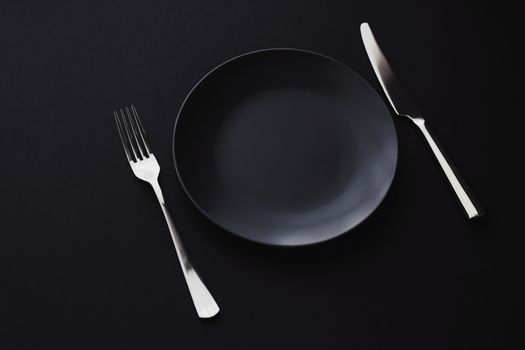 Empty plates and silverware on black background, premium tableware for holiday dinner, minimalistic design and diet concept