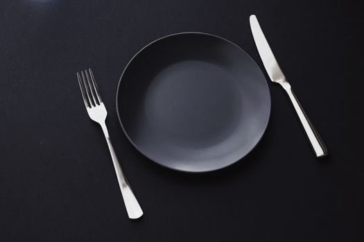 Empty plates and silverware on black background, premium tableware for holiday dinner, minimalistic design and diet concept