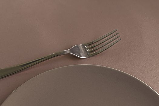 Empty plate and cutlery as mockup set on brown background, top tableware for chef table decor and menu branding design