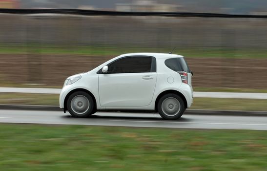 A panning shot of a speeding small car